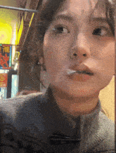 a woman smoking a cigarette with a sign in the background that says ' chinese ' on it