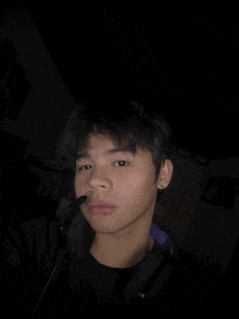 a young man wearing headphones and a microphone looks at the camera