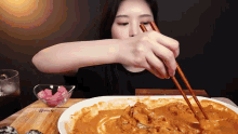 a woman is eating a plate of food with chopsticks ..