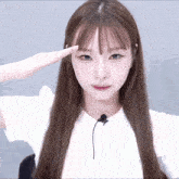a woman with long brown hair salutes with her hand on her forehead