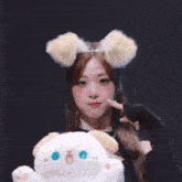 a woman wearing bunny ears is holding a stuffed animal that says uni on it