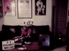 a man is sitting on a couch with a sign that says streamys mar 3rd