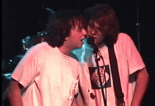 two men singing into microphones with one wearing a t-shirt with a picture of a monkey on it