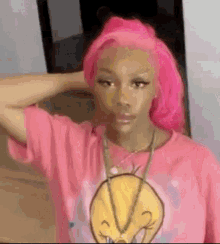 a girl with pink hair is wearing a pink t-shirt and a necklace .