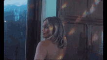 a naked woman is standing in front of a window