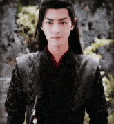 a young man with long hair is wearing a black jacket and a red collar