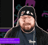 a man with a beard and glasses is wearing a black beanie and a blue shirt that says extra life