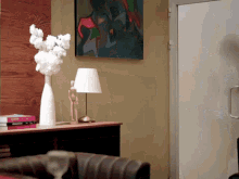 a vase of flowers sits on a table next to a lamp and a book that says ' fashion ' on it