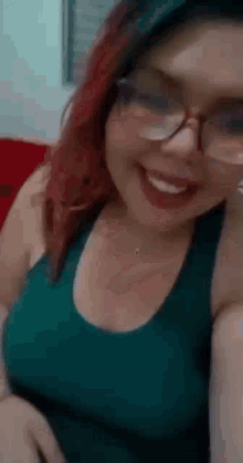 a woman wearing glasses and a green tank top is smiling and looking at the camera .