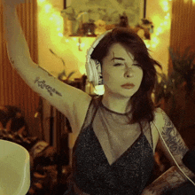 a woman wearing headphones has a tattoo on her arm that says " i love you "
