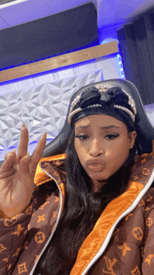 a woman wearing a louis vuitton jacket and headband giving a peace sign