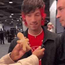 a man with red hair is holding a gingerbread man in his hands