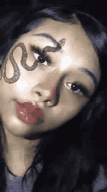 a woman with a snake on her face is taking a selfie .