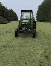 a green john deere tractor is driving through a lush green field