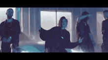 a group of people are dancing in a room in front of a car in a video .