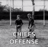 a black and white photo of two men playing football with the words `` chiefs offense '' written above them .