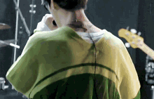 a close up of a person 's back with a guitar in the background