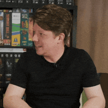 a man wearing a black shirt is sitting in front of a bookshelf with a book called eternity wars
