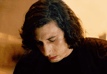 a man with long hair is sweating and looking down
