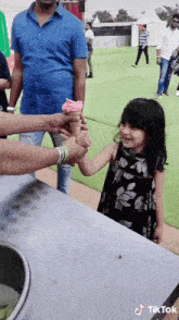 a little girl is being handed a pink ice cream cone by a man in a blue shirt