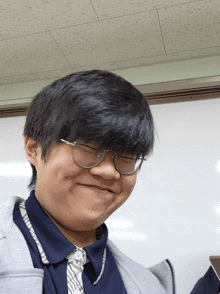 a young man wearing glasses and a plaid shirt smiles for the camera