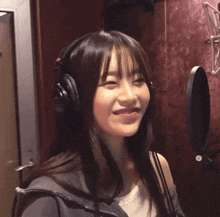 a woman wearing headphones is smiling and looking at the camera