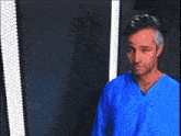 a man wearing a blue shirt is standing in front of a mirror