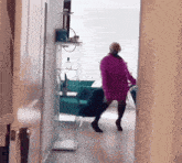 a woman in a purple coat and high heels is standing in a hallway