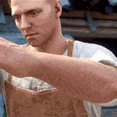a man wearing an apron and a white shirt holds his arm out