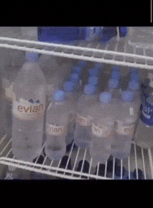 several bottles of evian water are lined up in a refrigerator
