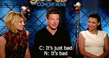 a man and two women sitting in front of a concert movie sign