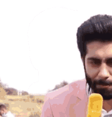 a man with a beard is holding a yellow ice cream cone .