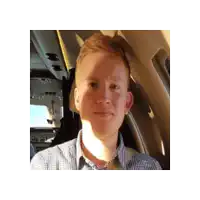a man in a plaid shirt is sitting in the back seat of a car .