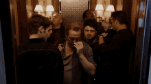 a group of men are standing in an elevator with one man smoking a cigar