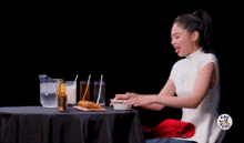 a woman is sitting at a table with a bottle of beer and a pitcher of milk .