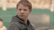 a young man with red hair is wearing a gray jacket and a hoodie .