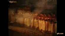 a group of people are dancing and holding candles in a dark room .