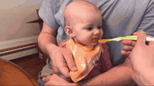 a baby wearing a bib with a deer on it is being fed by a man