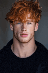 a young man with red hair and freckles looks at the camera