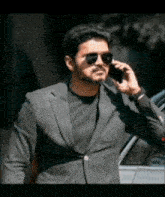 a man in a suit and sunglasses is talking on his cell phone