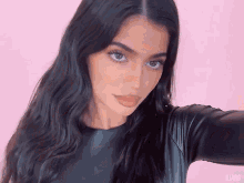 a close up of a woman 's face with a pink background and the word kjarg on the bottom