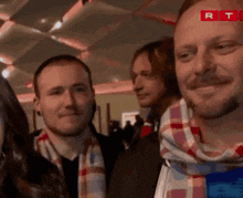 a man with a scarf around his neck is smiling in front of a red rt logo