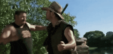 a man in a cowboy hat is standing next to another man in a black vest .