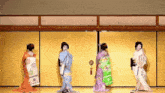a group of geishas are dancing in a room with a yellow wall .
