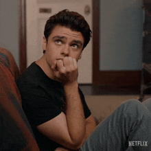 a man sitting on a couch with a netflix logo on the bottom right