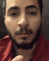 a man with a beard and a red shirt looks at the camera