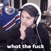 a man wearing headphones and a hat says " what the fuck " in front of a microphone
