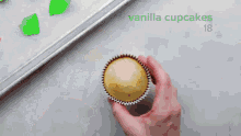 a person is frosting a cupcake with a piping bag .