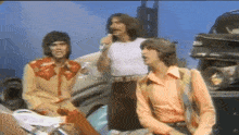 a group of men are standing next to each other and one has a microphone in his mouth