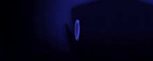 a green shield is glowing in the dark against a dark blue background .